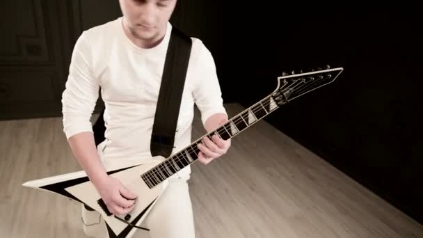 Elegante guitarrista solo com dreadlocks em sua cabeça e em roupas brancas em um fundo preto tocando expressivamente a guitarra branca em um estúdio preto — Vídeo de Stock