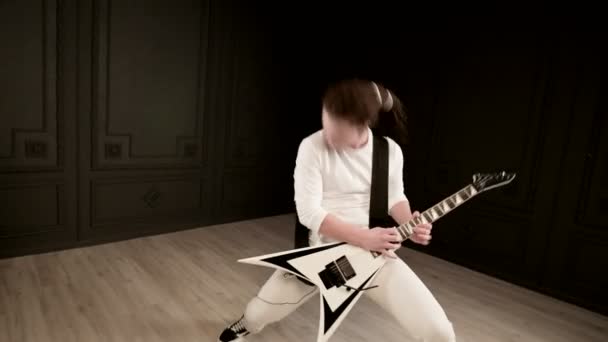 Elegantní sólový kytarista s dredy na hlavě a v bílých šatech na černém pozadí, který významně hraje bílou kytaru v černém studiu — Stock video