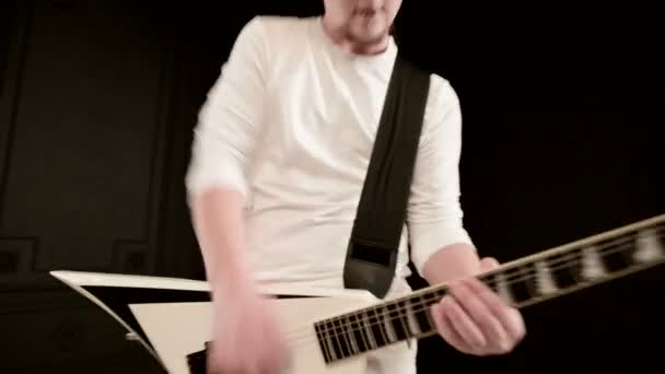Κομψό σόλο κιθαρίστα με ντρέσλοκ στο κεφάλι του και σε λευκά ρούχα σε ένα μαύρο φόντο με εκφραστικά παιχνίδια με τη λευκή κιθάρα σε ένα μαύρο στούντιο — Αρχείο Βίντεο
