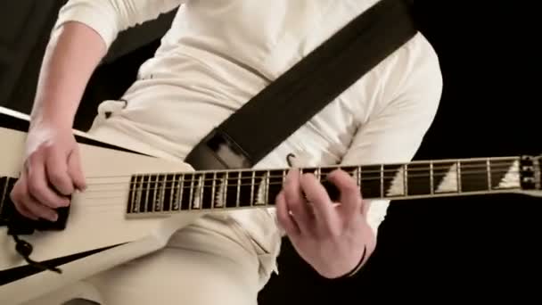 Close-up Guitarrista solo elegante com dreadlocks em sua cabeça e em roupas brancas em um fundo preto tocando expressivamente a guitarra branca em um estúdio preto — Vídeo de Stock