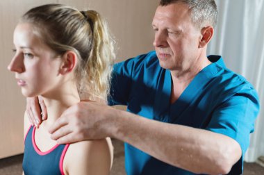 Erkek manuel visseral terapist masör genç bir kadın hasta davranır. Omuzları ve boynu ısıtın