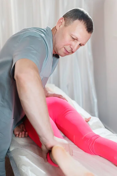 Masajista manual visceral masculino trata a una paciente joven. Trabajar con las nalgas de la parte inferior de la espalda y los músculos pélvicos — Foto de Stock