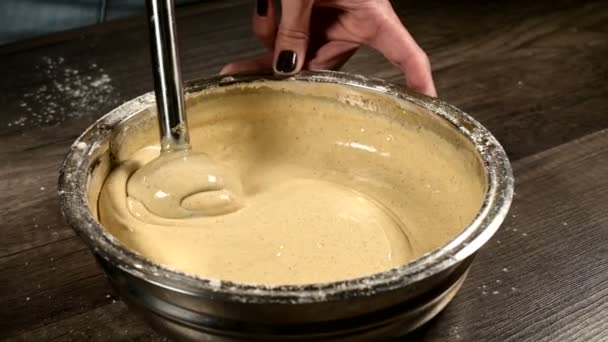 Primer plano de una pastelera en la cocina en un recipiente de metal con una licuadora batiendo la masa para la torta de esponja. Artículos de confitería casera — Vídeo de stock