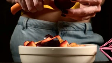 Bir ev mutfağında kadın elleri yakın çekim bir erik bıçağı ile taze çilek kesme ve limon bir sepet yanında onlardan bir kemik alarak. Sağlıklı gıda ve vitamin kavramı
