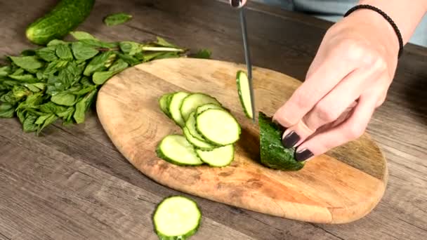 Uzavření ženských rukou krájení okurek na kočárku na řezací desce vedle nasekané lístky máty. Zdravé a zdravé vegetariánské potraviny — Stock video