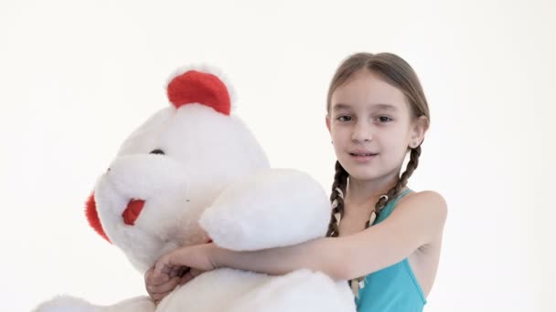 Porträtt av en söt vit flicka med Pigtails kramar med en stor nallebjörn på en vit bakgrund i studion — Stockvideo
