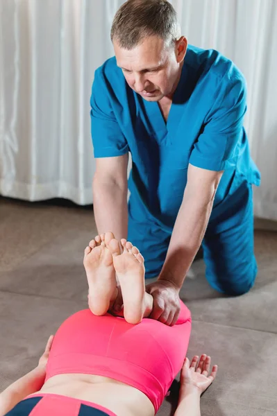 Un fisioterapeuta masculino está estirando las articulaciones de la rodilla a una paciente joven. Terapia de Bienestar Manual — Foto de Stock