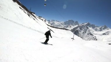 Siyah ekipman ve kayak direkleri ile beyaz kask yaşlı geniş açılı erkek kayakçı güneşli bir günde karlı bir yamaç üzerinde sürmek. Kış kayak sporları kavramı