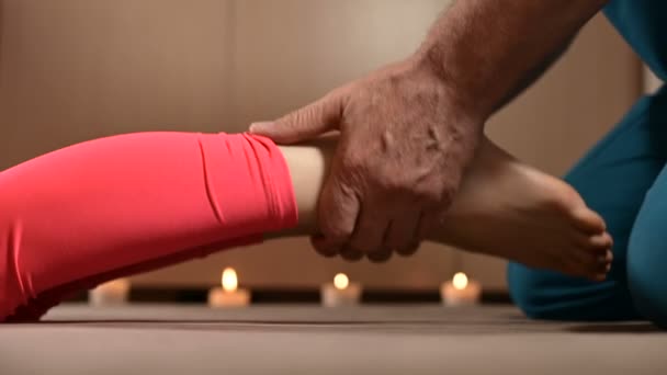 In Großaufnahme streckt ein männlicher Physiotherapeut einer jungen Patientin die Kniegelenke entgegen. Manuelle Wellnesstherapie — Stockvideo