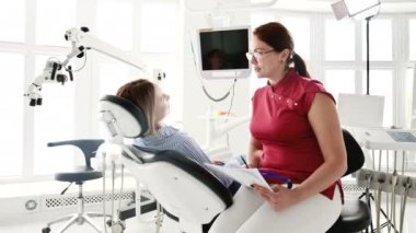 Gözlüklü bir diş hekimi kadın ile istişare genç bir kız bir stamotoloji ofisinde bir sandalyede oturuyor. Doktor ve hastanın konuşma