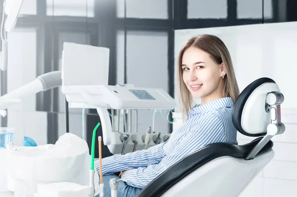歯科椅子に座った魅力的な笑顔の女の子ブロンドの肖像画。幸せな顧客の歯科キャビネット — ストック写真