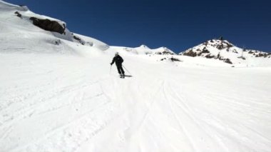 Siyah ekipman ve kayak direkleri ile beyaz kask yaşlı geniş açılı erkek kayakçı güneşli bir günde karlı bir yamaç üzerinde sürmek. Kış kayak sporları kavramı