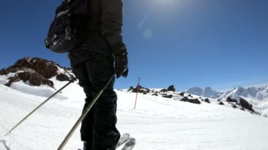 Siyah ekipman ve kayak direkleri ile beyaz kask yaşlı geniş açılı erkek kayakçı güneşli bir günde karlı bir yamaç üzerinde sürmek. Kış kayak sporları kavramı