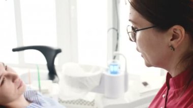 Gözlüklü bir diş hekimi kadın ile istişare genç bir kız bir stamotoloji ofisinde bir sandalyede oturuyor. Doktor ve hastanın konuşma