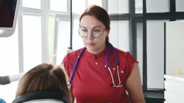 Gözlüklü bir diş hekimi kadın ile istişare genç bir kız bir stamotoloji ofisinde bir sandalyede oturuyor. Doktor ve hastanın konuşma