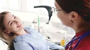 Gözlüklü bir diş hekimi kadın ile istişare genç bir kız bir stamotoloji ofisinde bir sandalyede oturuyor. Doktor ve hastanın konuşma