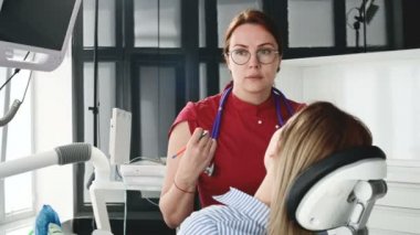 Gözlüklü bir diş hekimi kadın ile istişare genç bir kız bir stamotoloji ofisinde bir sandalyede oturuyor. Doktor ve hastanın konuşma