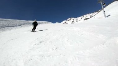 Siyah ekipman ve kayak direkleri ile beyaz kask yaşlı geniş açılı erkek kayakçı güneşli bir günde karlı bir yamaç üzerinde sürmek. Kış kayak sporları kavramı