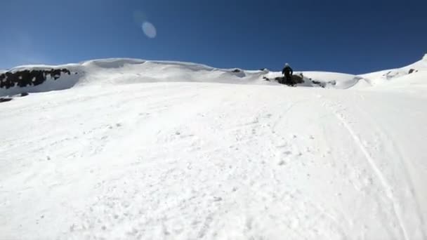 在阳光明媚的日子里，一名身着黑色装备、头戴白色头盔、带滑雪杆的广角男性滑雪者在雪坡上骑行。冬季滑雪运动的概念 — 图库视频影像