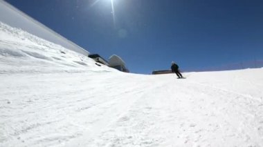 Siyah ekipman ve kayak direkleri ile beyaz kask yaşlı geniş açılı erkek kayakçı güneşli bir günde karlı bir yamaç üzerinde sürmek. Kış kayak sporları kavramı