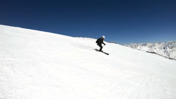 Siyah ekipman ve kayak direkleri ile beyaz kask yaşlı geniş açılı erkek kayakçı güneşli bir günde karlı bir yamaç üzerinde sürmek. Kış kayak sporları kavramı — Stok video