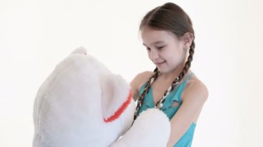 Stüdyoda beyaz bir arka plan üzerinde büyük bir oyuncak ayı ile sarılma pigtails ile sevimli bir beyaz kız Portresi