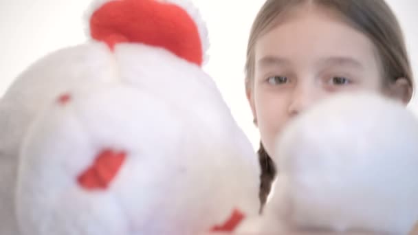 Retrato de una linda chica blanca con coletas abrazándose con un gran oso de peluche sobre un fondo blanco en el estudio — Vídeos de Stock