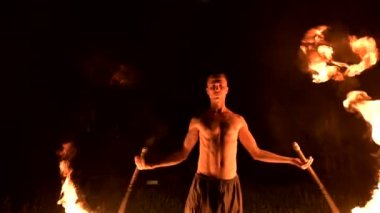 Düşük anahtar. Uzun saçlı ve çıplak gövde ile genç erkek siyah bir gece video yavaş hareket açık havada yanan meşale döner. Modern fakir bir yanan personel ile hileler yapar