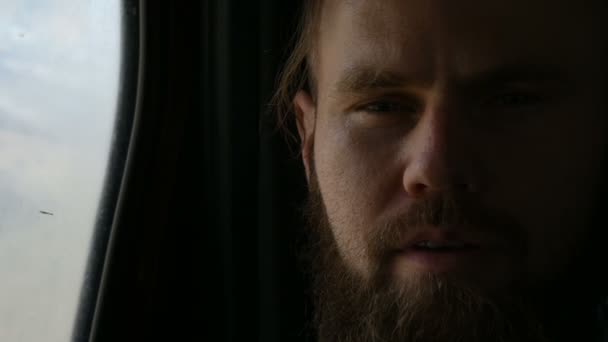 Close-up portrait of a talking bearded hipster male sitting in the car in the backseat and meditating on the sides against the background of mountains — Stock Video