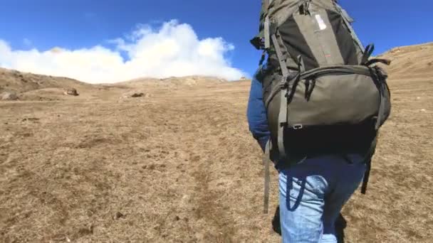 Due fotografi turisti con zaini in cappelli e occhiali da sole salgono sulla collina sull'erba gialla con le macchine fotografiche in mano sullo sfondo di montagne innevate. rallentatore — Video Stock