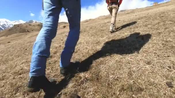 Ноги двух туристов путешественников фотографы идут в гору в солнечный день — стоковое видео