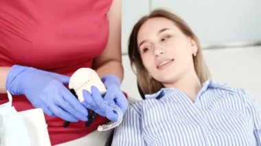 Kadın diş hekimi genç kadın hastaya alçı modeli ile ilgili sorunu gösteriyor ve açıklıyor