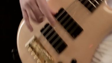 Siyah bir arka plan üzerinde bej bas gitar ile beyaz giysiler içinde genç erkek müzisyen. Bas gitarist anlamlı müzik oyunu