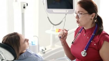 Gözlüklü bir diş hekimi kadın ile istişare genç bir kız bir stamotoloji ofisinde bir sandalyede oturuyor. Doktor ve hastanın konuşma