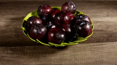 Ahşap bir masa üzerinde yeşil bir kapta olgun taze iştah açıcı erik Closeup. Sağlıklı yiyecekler. Yaz diyeti