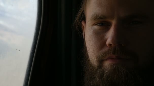 Close-up portret van een bebaarde hipster mannetje zittend in de auto op de achterbank en mediteren aan de zijkanten tegen de achtergrond van de bergen — Stockvideo