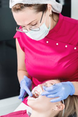 Diş hekimi sandalyesinde yakın çekim genç bir kız temizlik ve boyutlandırma ile parantez çıkardıktan sonra rutin bir tanı uğrar. Yaşamda ve klinikte stamatoloji