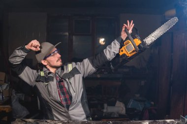 Bir vücut geliştirmeci temsil eden bir poz elinde bir testere ile bir atölyegenç bir marangoz Portresi. Şakalar ve işyeri marangoz eğlenceli