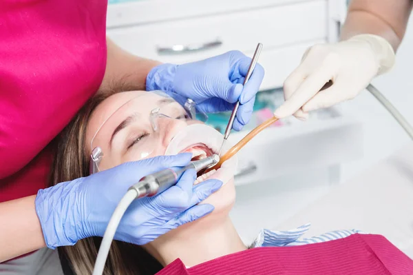 Il primo piano di una giovane ragazza su una sedia da dentista viene sottoposto a una diagnosi di routine dopo aver rimosso l'apparecchio con pulizia e dimensionamento. Stamatologia nella vita e nella clinica — Foto Stock