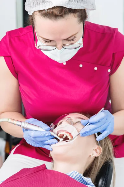 Крупным планом молодая девушка в кресле стоматолога подвергается стандартному диагнозу после удаления брекетов с уборкой и размером. Стаматология в жизни и в клинике — стоковое фото
