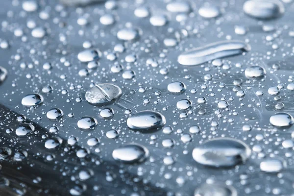 Close-up of raindrops of different sizes on the surface covered with cling film. Moisture weather and humidity concept