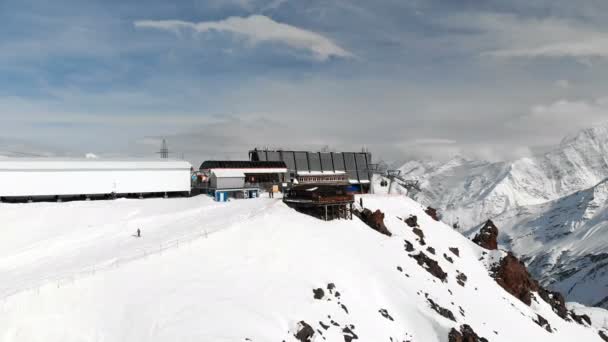 Aerial view station of a ski lift with cabins high in the Caucasus Mountains in the resort of Elbrus in the winter season. Station and cableway overview — Stock Video