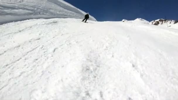 Siyah ekipman ve kayak direkleri ile beyaz kask yaşlı geniş açılı erkek kayakçı güneşli bir günde karlı bir yamaç üzerinde sürmek. Kış kayak sporları kavramı — Stok video