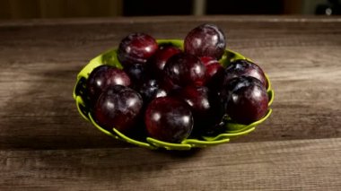 Ahşap bir masa üzerinde yeşil bir kapta olgun taze iştah açıcı erik Closeup. Sağlıklı yiyecekler. Yaz diyeti