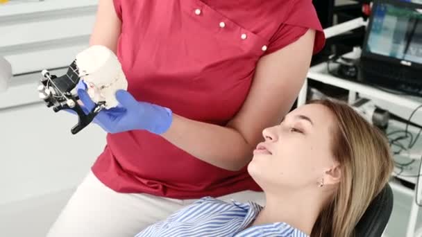 Dentista feminino mostra e explica problema no modelo de gesso para paciente jovem — Vídeo de Stock
