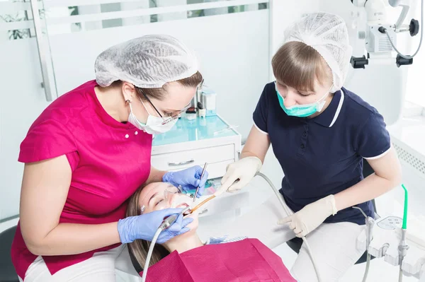 Γυναίκα οδοντίατρος και νοσοκόμα κάνει επαγγελματική φροντίδα και οδοντικό βούρτσισμα ενός νεαρού ασθενούς σε ένα οδοντιατρείο — Φωτογραφία Αρχείου