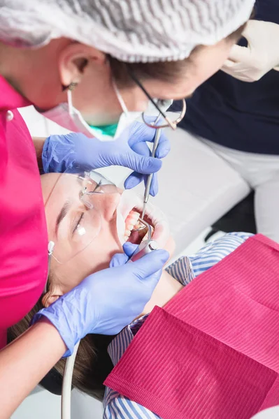 Dentista e enfermeira fazendo cuidados profissionais e escovação de dentes de um paciente jovem em um consultório odontológico — Fotografia de Stock