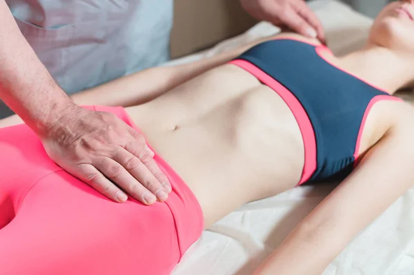 Il massaggiatore viscerale manuale maschile tratta una giovane paziente donna. Riscaldamento esterno dell'utero con l'energia delle mani — Foto Stock