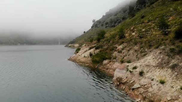 Vista aérea de uma costa rochosa. Montanha lago azul-turquesa entre as colinas em tempo nublado e nevoeiro. Paisagens do Norte do Cáucaso — Vídeo de Stock