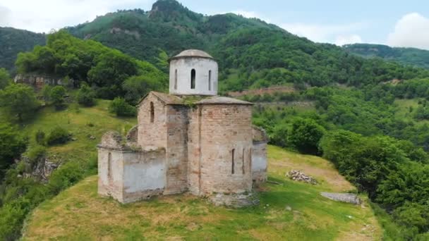 空中写真 カラチャイ・チェルケシア共和国の白人の山々で10世紀の古代の部分的に破壊されたキリスト教の教会 — ストック動画